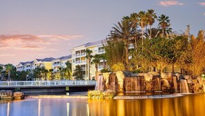 A resort with a water feature, palm trees, and a bridge. - 2-bedroom Resort Villa in Orlando-Universal, Disney, Epcot (Orlando)