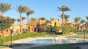 A resort with a swimming pool, palm trees, and traditional architecture.