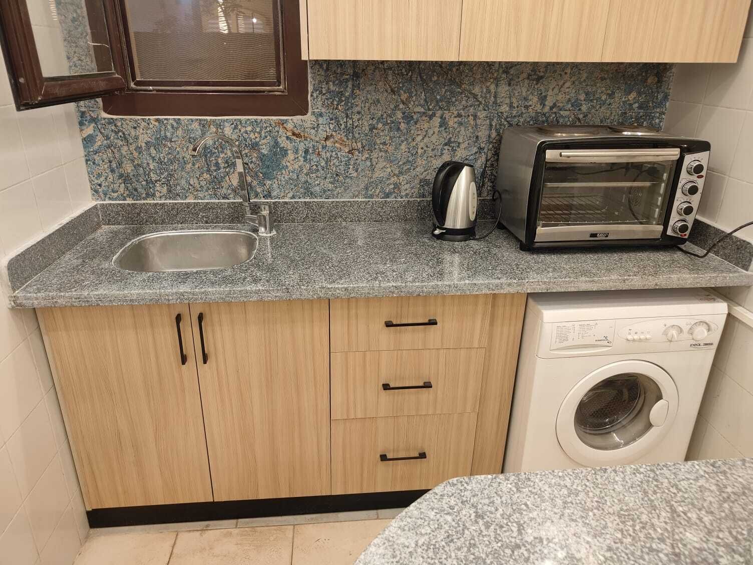 Eine kleine Küche mit Spüle, Toaster, Wasserkocher und Waschmaschine.