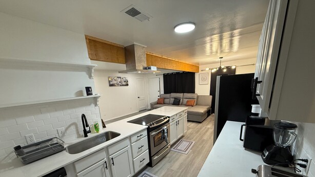A compact kitchen with white cabinetry, a built-in oven, a sink, and a toaster.