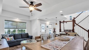 A spacious living room with a dark gray sofa, a wooden dining table, and a ceiling fan. - Professionally Managed | Walk to Beach (Seaside Heights)