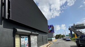 A large industrial building with a closed shutter, a yellow curb, and a clear sky. - HOSTEL OF SANTURCE (San Juan)