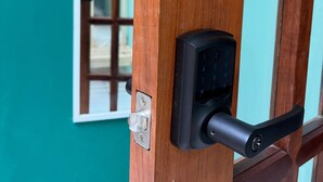 A wooden door with a modern electronic lock and a window with a grid pattern. - HOSTEL OF SANTURCE (San Juan)
