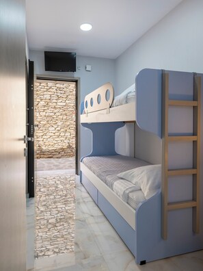 A bunk bed room with a stone wall, a door, and a tiled floor. - Πολυτελής σουιτα με ιδιωτικη πισινα και υπέροχη θέα στο Αιγαίο! (Paros)