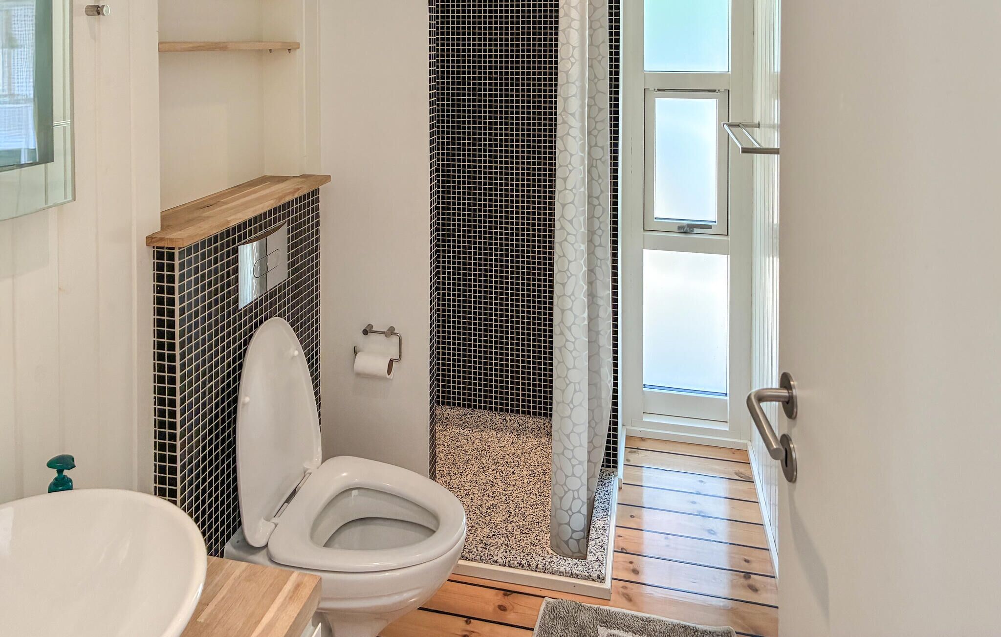 Un baño con inodoro, lavamanos y zona de ducha.