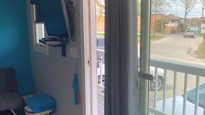 A room with a blue wall, a window with a view of a street, a desk with a computer, and a chair. - 2BR Room at Alexander’s Landing. Walk to Indiana Beach + Pool Access (Monticello)