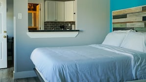 A bedroom with a bed, a built-in bench with a mirror, and a view into the kitchen. - Relax & Recharge – Lake Views Just Outside Your Door (Monticello)