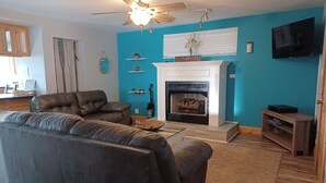 A living room with a fireplace, a sofa, a coffee table, and a television. - 3 Bedroom Suite, just steps from Indiana Beach with lake access and more! (Monticello)