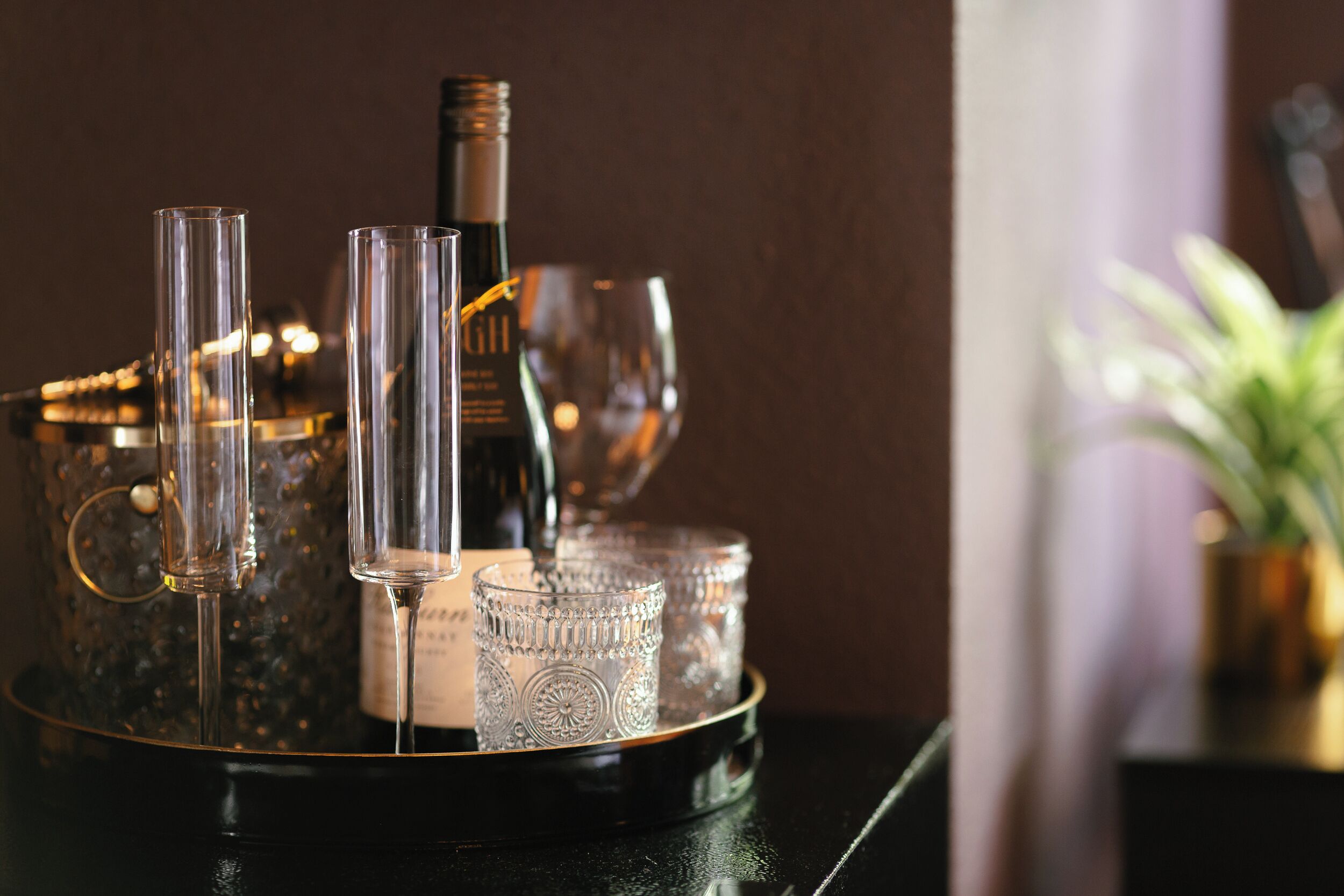 A tray with wine glasses, a bottle, and a decorative container on a table.
