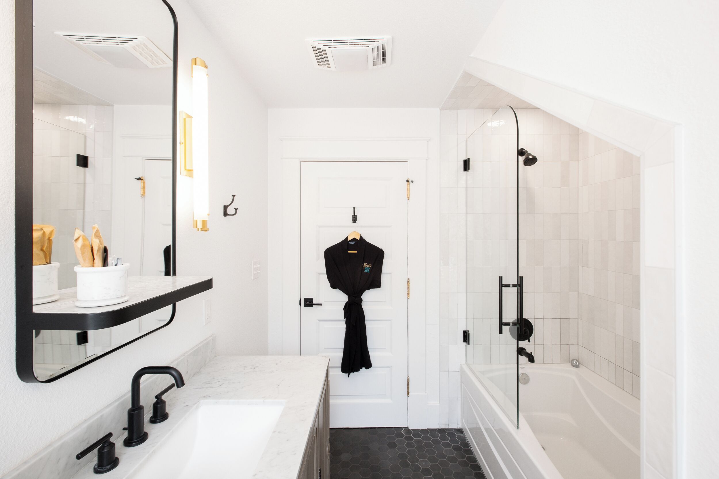 A modern bathroom with a white sink, black faucet, and a glass shower enclosure.