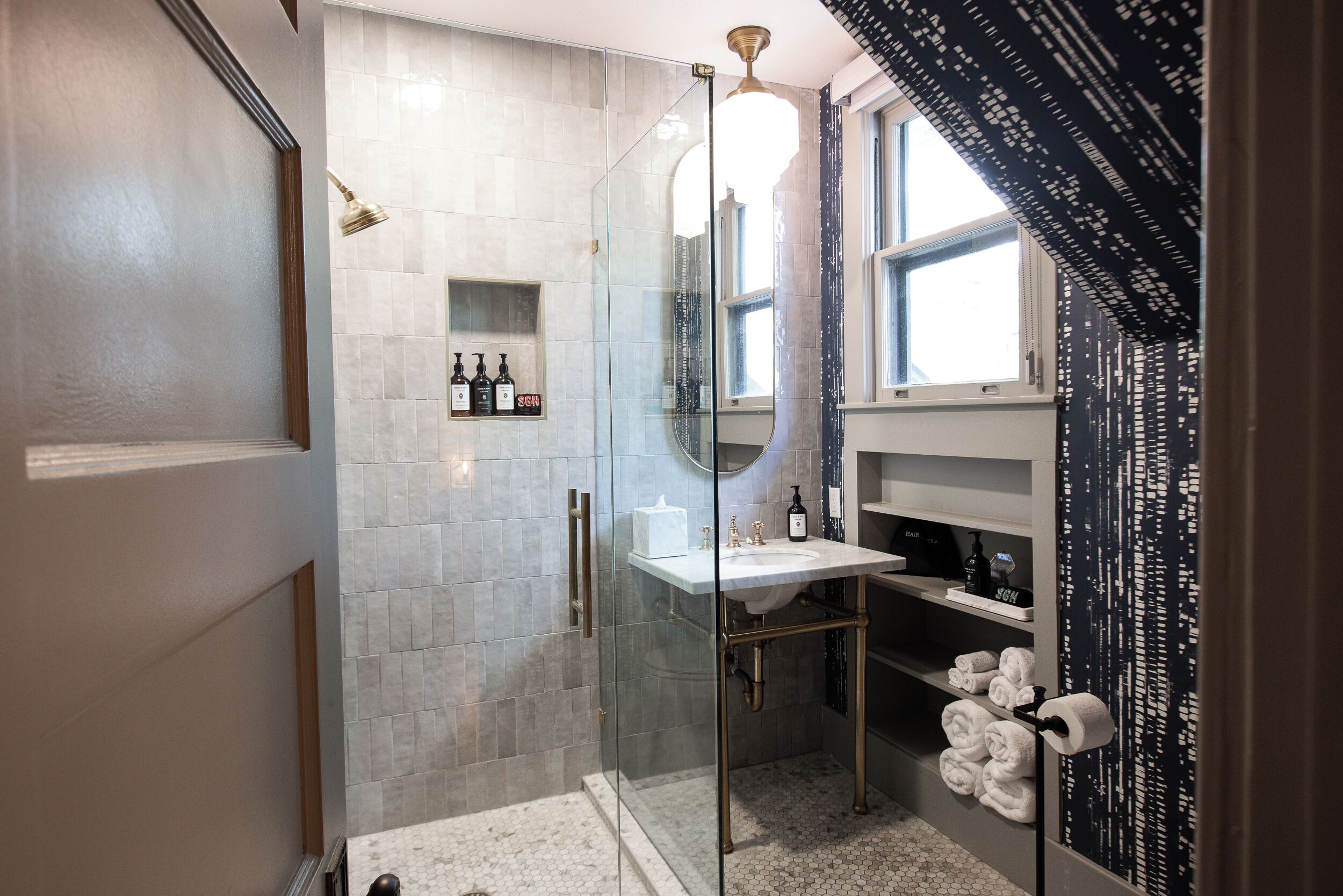 A modern bathroom with a glass-enclosed shower, a white sink, and a towel rack.