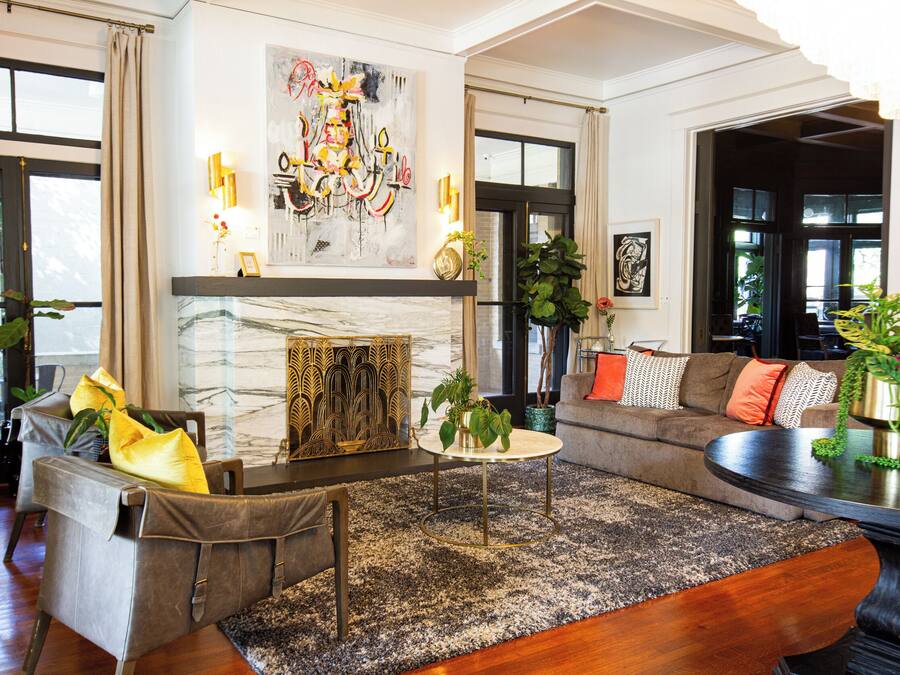 A modern living room with a fireplace, a sofa, a coffee table, and various decorative plants.