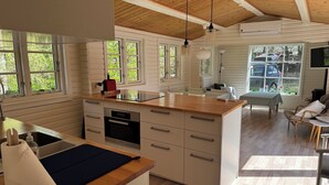 Una cocina moderna con una isla de madera, horno empotrado y comedor con mesa y sillas.