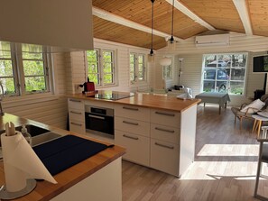 A modern kitchen with a wooden island, built-in oven, and a dining area with a table and chairs.