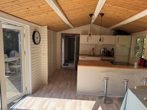 A modern kitchen with wooden ceiling beams, a central island, and bar stools. - Cottage at Nordstrand (Nykøbing Sj)