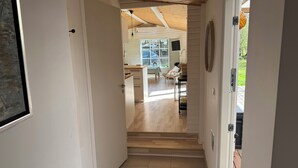 Un pasillo con techo de madera, un comedor con mesa y sillas, y vistas al exterior.