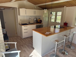 A kitchen with white cabinets, a wooden countertop, a sink, a coffee maker, and a refrigerator.