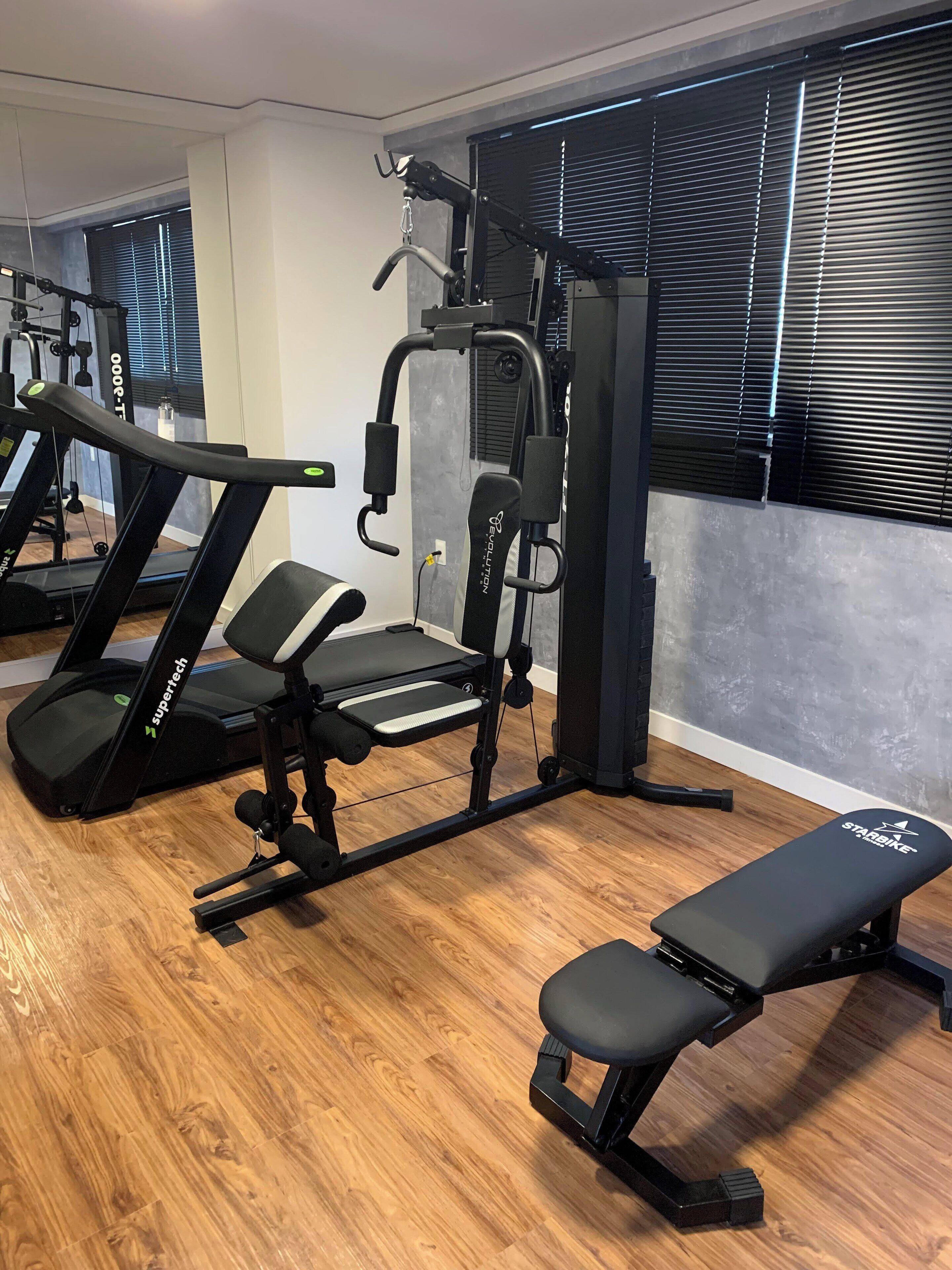 A gym with exercise equipment including treadmills, a bench, and weight machines.