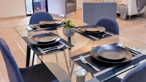 A dining area with a glass table set for four, surrounded by dark blue chairs. - Rango #3 – Your Perfect Space in Cabrera (Cabrera)