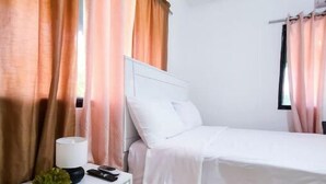 A bedroom with a bed, a nightstand, a lamp, and curtains. - Rango #3 – Your Perfect Space in Cabrera (Cabrera)