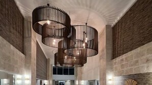 A spacious lobby with a marble floor, a central spiral staircase, and a modern chandelier.