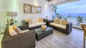 A modern living room with a sofa set, coffee table, and a view of the ocean.