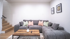 Una sala de estar moderna con un sofá seccional gris, una mesa de centro de madera y un jarrón con flores.