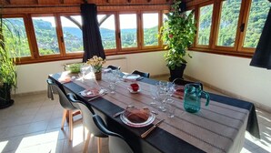 A dining area with a table set for six, large windows, and a view of the outdoors. - Gîtes de France® - L'Oustal de Marguerite (SAINT SULPICE)