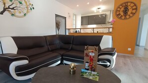 A modern living room with a sectional sofa, a round coffee table, and a decorative wall piece. - Gîtes de France® - L'Oustal de Marguerite (SAINT SULPICE)