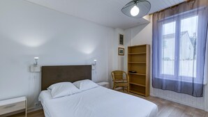 A bedroom with a bed, a chair, a wardrobe, and a window with curtains. - 1 bedroom cozy home in La Rochelle (La Rochelle)