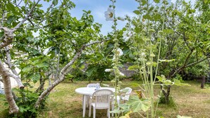A garden with a dining table and chairs, surrounded by trees and a plant with white flowers. - 1 bedroom cozy home in La Rochelle (La Rochelle)