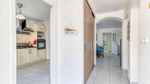 Una cocina moderna con armarios blancos, un microondas y una estufa. Un letrero con la palabra 'Welcome' está colgado en la pared.