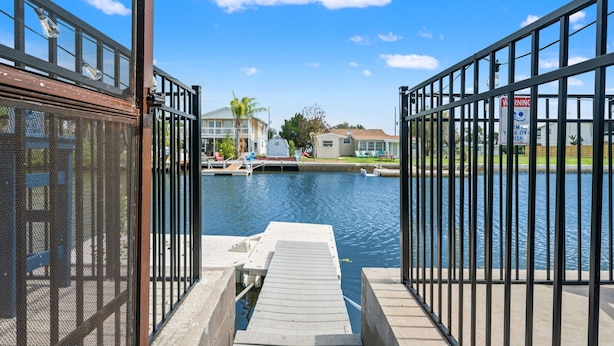 A marina with docked boats, a clear sky, and a residential area in the background. - 6BR Waterfront • Direct Gulf • Fire Pit • Biliards (Hernando Beach)