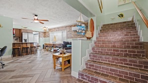 A spacious living area with a herringbone floor, a brick staircase, and a kitchen with a brick backsplash. - 6BR Waterfront • Direct Gulf • Fire Pit • Biliards (Hernando Beach)