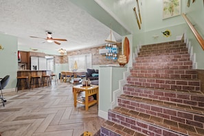 A spacious living area with a herringbone floor, a brick staircase, and a kitchen with a brick backsplash. - 6BR Waterfront • Direct Gulf • Fire Pit • Biliards (Hernando Beach)