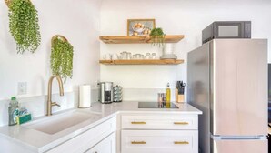 A kitchen with white cabinets, a stainless steel refrigerator, and hanging plants. - Forest Studio Oasis - Mile from Multnomah Village (Portland)