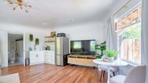 A modern kitchen with wooden flooring, a built-in fridge, a TV, and a dining area with a round table and chairs. - Forest Studio Oasis - Mile from Multnomah Village (Portland)