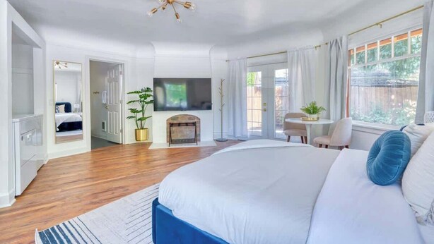 Quarto com cama grande, televisão, lareira e vista para o exterior.