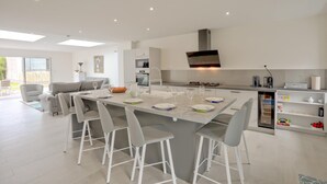 A modern kitchen with a central island, bar stools, and a dining area.