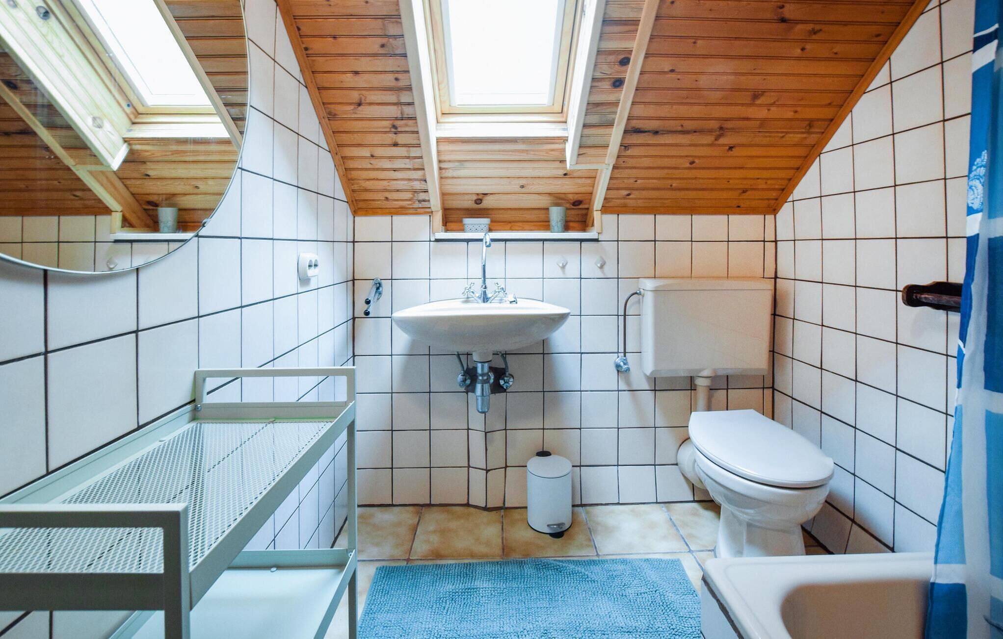 Une petite salle de bain dotée d’un puits de lumière, d’un lavabo, de toilettes et d’un espace douche.
