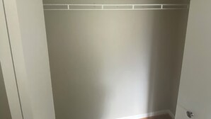 Ein Zimmer mit Holzboden, einer weißen Tür und einer weißen Decke mit Zierleisten.