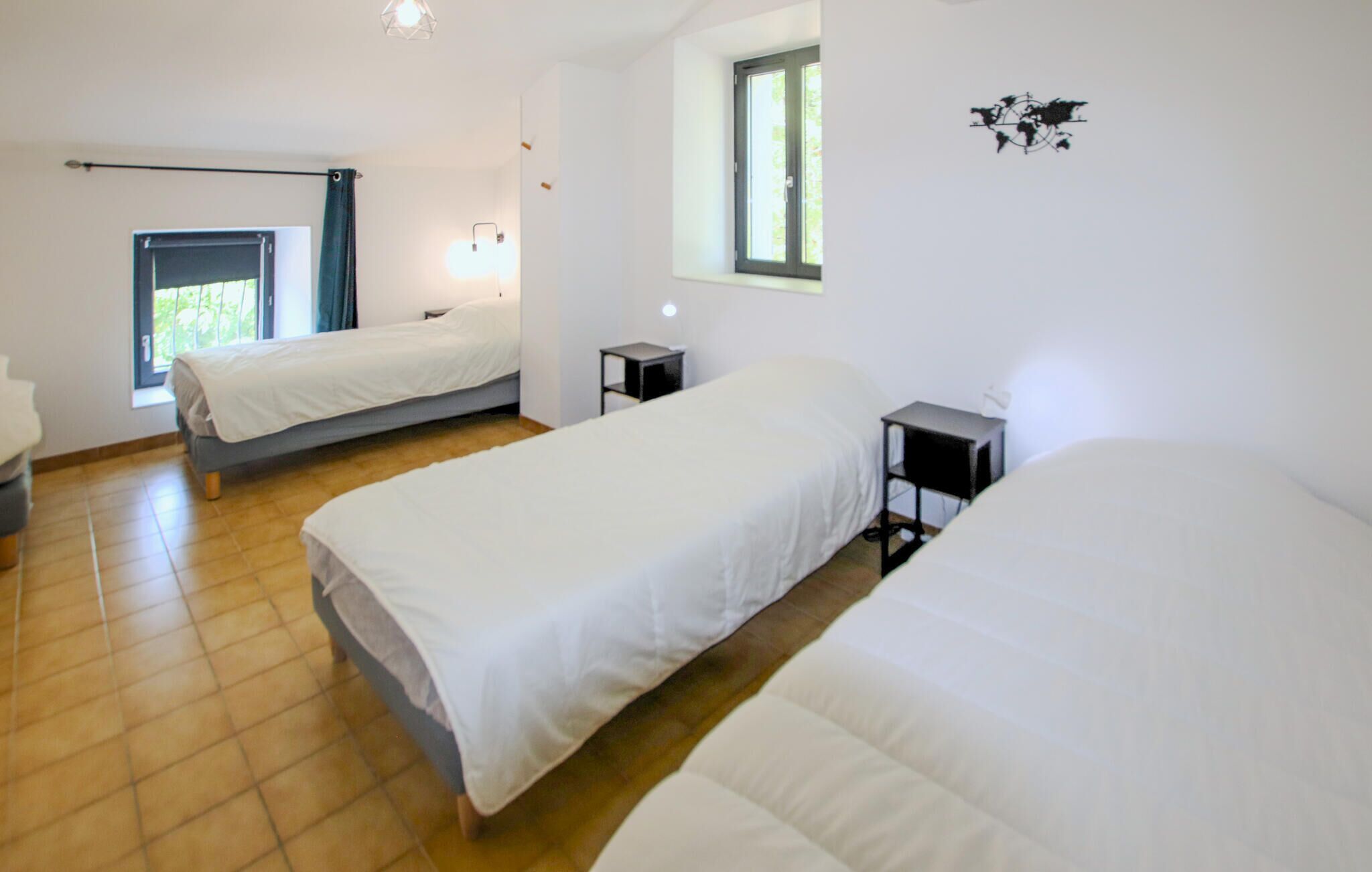 A room with three beds, a window, and a wall-mounted light fixture.