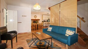 A living room with a blue sofa, a wooden coffee table, and a patterned rug. There is a dining area with chairs and a table in the background. - Gorgeous home in Balazuc with private swimming pool, can be inside or outside (Balazuc)