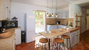 A modern kitchen with white cabinets, a built-in oven, a refrigerator, and a wooden island with stools. - Gorgeous home in Balazuc with private swimming pool, can be inside or outside (Balazuc)