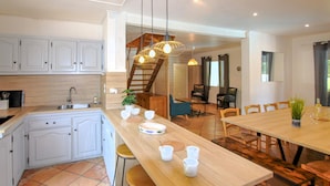 A modern kitchen with white cabinets, a wooden countertop, and a dining area with a wooden table and chairs. - Gorgeous home in Balazuc with private swimming pool, can be inside or outside (Balazuc)