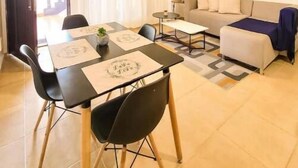 Un salon moderne comprenant un coin repas, un canapé, un ventilateur de plafond et un tableau accroché au mur.