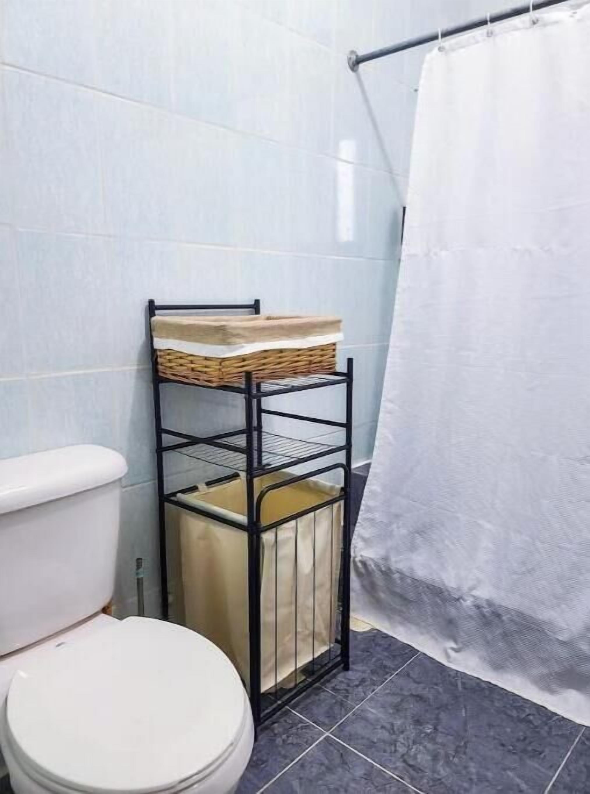 Ein Badezimmer mit Toilette, einem Metallregal mit Körben und einer Duschvorhang.