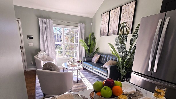 Un coin repas avec une table en marbre dressée pour quatre personnes, un lustre moderne et une vue sur le salon à travers une porte vitrée.