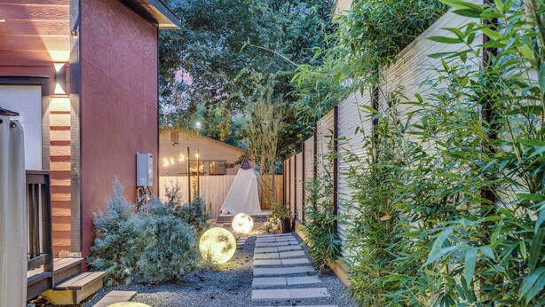 A pathway leading to a building with a wooden deck and a small garden area with a large spherical object. - Walkable East Austin Oasis with Jacuzzi (Austin)
