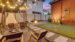 A backyard with a fire pit, outdoor seating, a tent, and a small lawn. - Walkable East Austin Oasis with Jacuzzi (Austin)